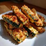 A close-up shot of crispy air fryer zucchini fries, coated in breadcrumbs and seasoned.