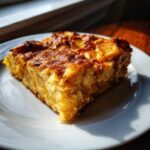 A slice of warm apple pie oatmeal bake on a white plate, with visible chunks of apple and a golden-brown topping.