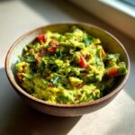 Close-up of a bowl of authentic guacamole, featuring chunky avocado, diced tomatoes, and fresh cilantro.