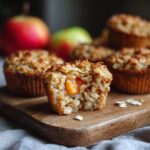 Close-up of a baked apple oatmeal cup with a bite taken out, revealing soft apple pieces inside.