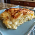 A close-up of a slice of golden-brown cheese blintz casserole on a blue plate.