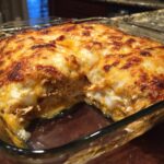 A close-up of a freshly baked chicken tortilla casserole in a glass dish, with golden melted cheese.