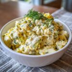 A bowl of creamy classic egg salad, garnished with fresh dill.