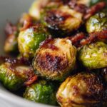Close-up of crispy roasted brussels sprouts with bacon pieces mixed throughout.