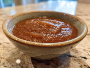 A close-up of a rustic bowl filled with rich, smooth crockpot apple butter.