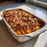 A close-up view of an easy apple crisp baked in a white rectangular baking dish, with a golden-brown crumble topping.