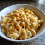 A close-up shot of a bowl filled with creamy homemade mac and cheese, showing melted cheese strings.