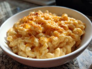A close-up of creamy homemade mac and cheese in a white bowl, topped with melted cheese.