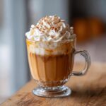 A delicious homemade pumpkin spice latte in a glass mug, topped with whipped cream and cinnamon.