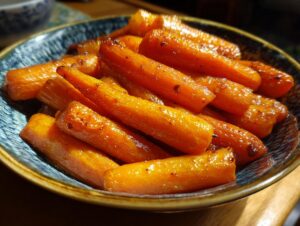 Close-up of a bowl filled with glistening honey glazed carrots, ready to be served.