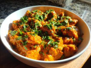 A bowl of creamy Instant Pot Chicken Tikka Masala, generously garnished with fresh chopped cilantro.
