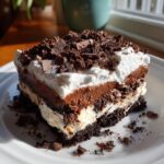 A decadent slice of no bake chocolate lasagna, layered with chocolate pudding, whipped cream, and chocolate shavings.