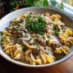 A close-up of a bowl of one pot beef stroganoff with tender beef and creamy sauce over egg noodles, garnished with fresh parsley.