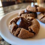 Close-up of a soft peanut butter blossom cookie topped with a shiny chocolate kiss.