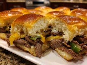 Close-up of delicious Philly cheesesteak sliders with melted cheese, steak, and green peppers on soft buns.