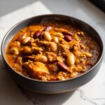 A steaming bowl of pumpkin turkey chili with kidney beans and cannellini beans.