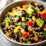 Close-up of a vibrant quinoa black bean salad with corn, diced tomatoes, avocado, and cilantro.