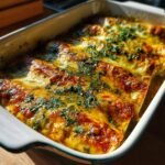 Close-up of baked Salsa Verde Chicken Enchiladas in a white baking dish, topped with melted cheese and chopped cilantro.
