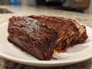 Close-up of tender, juicy slow cooker beef brisket slices on a white plate.