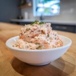 A white bowl filled with creamy smoked salmon dip, garnished with fresh dill.