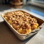 Close-up of a freshly baked apple crisp in a rectangular baking dish, with a golden brown, crumbly topping.