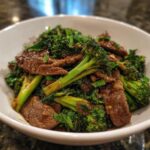 Close-up of a bowl filled with tender slices of beef and vibrant green broccoli florets in a savory sauce.