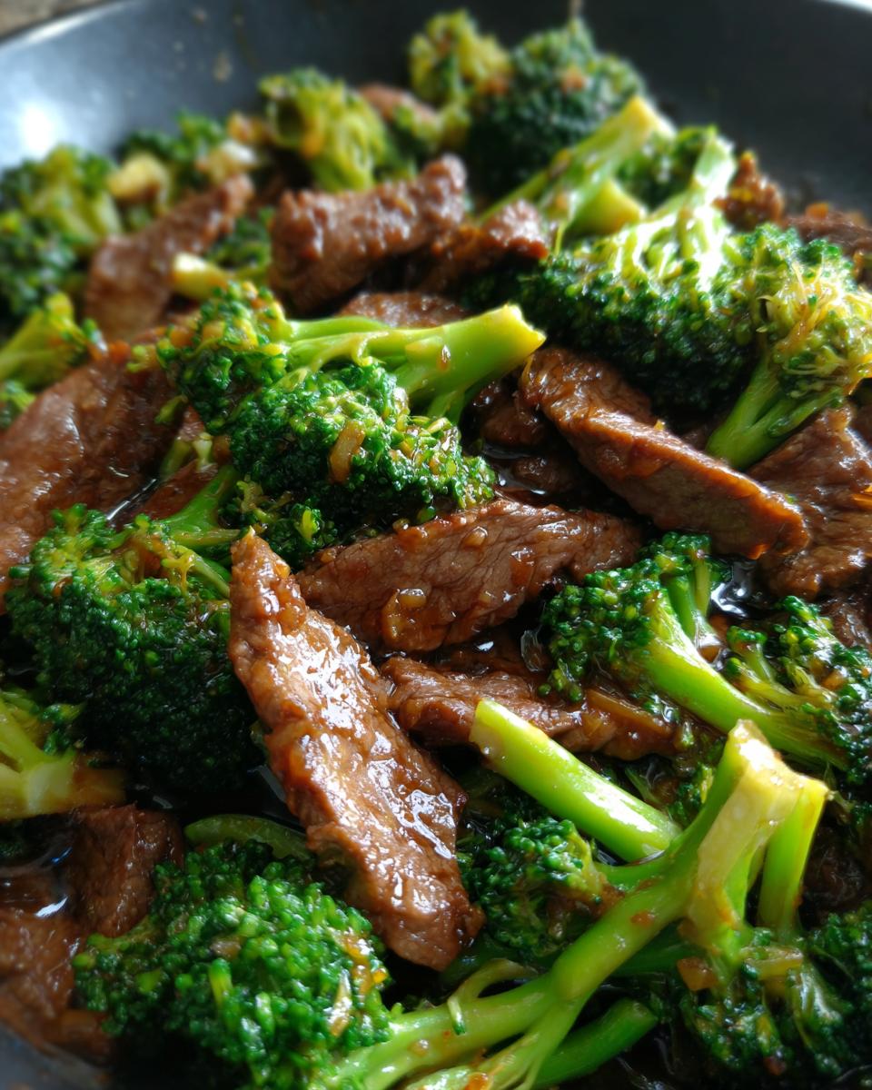 Close-up of tender slices of beef and vibrant broccoli florets coated in a savory sauce, a perfect beef and broccoli dish.