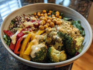 A vibrant and healthy Buddha bowl filled with quinoa, chickpeas, roasted broccoli, bell peppers, and a creamy dressing.