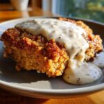 Close-up of a perfectly cooked chicken fried steak generously topped with creamy, peppery gravy.