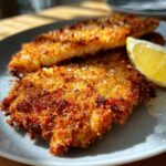 Close-up of golden-brown, crispy Schnitzel served with a fresh lemon wedge on a plate.