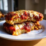 Two stacked slices of crispy Eggplant Parmesan with marinara sauce and melted mozzarella cheese.
