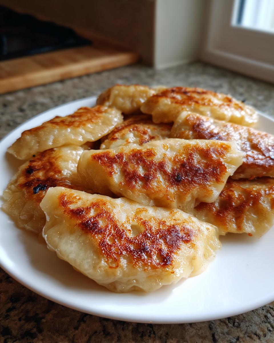 A close-up shot of a plate filled with perfectly pan-fried potstickers, showcasing their golden-brown, crispy bottoms.