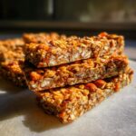 A close-up stack of delicious homemade granola bars, featuring oats, nuts, and seeds.