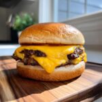 A close-up of a perfect juicy cheeseburger with two beef patties and melted cheddar cheese.