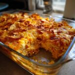 A close-up of a freshly baked King Ranch Chicken Casserole in a glass baking dish, topped with melted cheese and tortilla chips.
