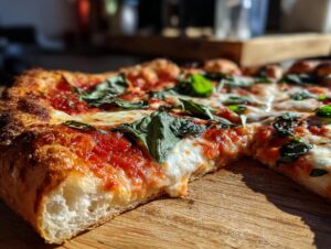 Close-up of a slice of Margherita pizza with melted mozzarella, tomato sauce, and fresh basil leaves.