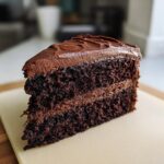 A decadent slice of moist chocolate cake with rich chocolate frosting, showcasing its layers.