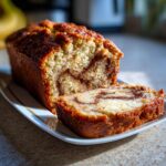 A close-up of a slice of moist zucchini bread with a beautiful cinnamon swirl inside.