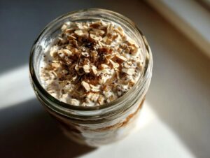 Close-up of overnight oats in a glass jar, topped with rolled oats, chia seeds, and a drizzle of honey.