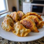 A plate full of golden-brown, pan-fried potstickers, showcasing their crispy bottoms and tender tops.
