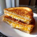 Close-up of a perfectly grilled cheese sandwich, cut in half, with melted cheese oozing out.