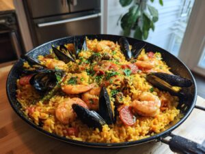 A close-up view of a vibrant seafood paella in a traditional pan, featuring rice, shrimp, mussels, and chorizo.