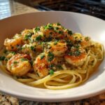 A close-up of a bowl of shrimp scampi, featuring plump shrimp tossed with linguine and fresh parsley.