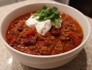 A bowl of hearty slow cooker chili topped with sour cream and cilantro.