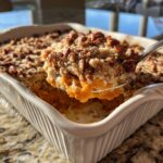 A spoonful of creamy sweet potato casserole topped with crunchy pecans and crumble.