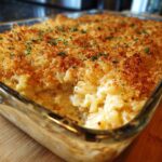 A close-up of a freshly baked tuna noodle casserole in a glass baking dish, topped with golden breadcrumbs and parsley.