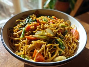 A bowl of delicious Vegetable Lo Mein with noodles, carrots, bok choy, and onions.