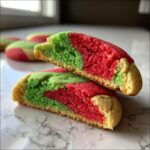 Close-up of a 3-color pinwheel cookie cut in half, showing red, green, and white dough layers.