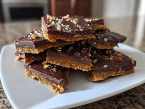 A stack of rich graham cracker toffee squares topped with chocolate, nuts, and sea salt.