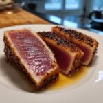 Three slices of perfectly seared tuna steak, crusted with sesame seeds, showing a rare, pink center.